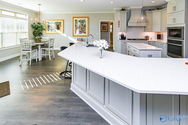 kitchen with a large island with sink, dark wood-type flooring, decorative light fixtures, gray cabinets, and custom exhaust hood