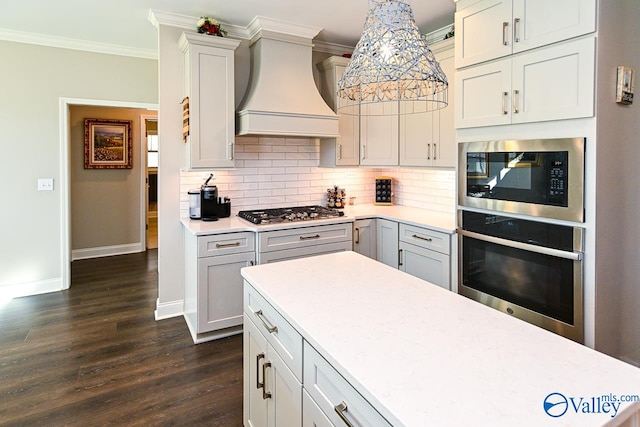 kitchen with stainless steel appliances, decorative light fixtures, dark wood-type flooring, ornamental molding, and premium range hood