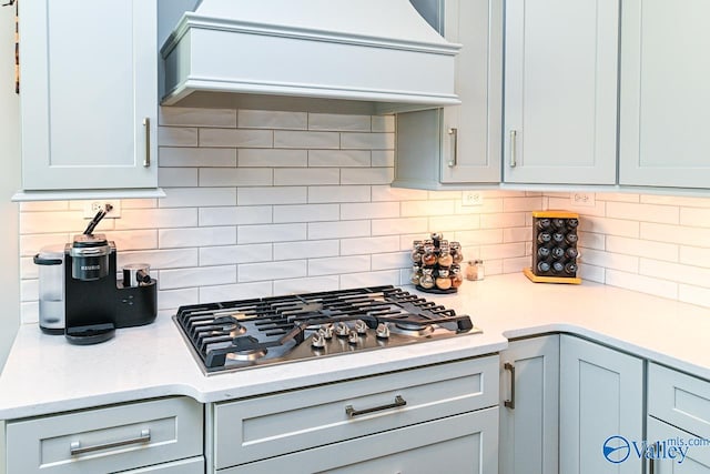 kitchen with stainless steel gas cooktop, custom range hood, and tasteful backsplash