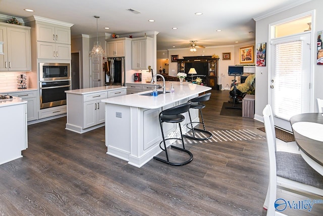 kitchen with decorative backsplash, a kitchen island with sink, sink, pendant lighting, and appliances with stainless steel finishes