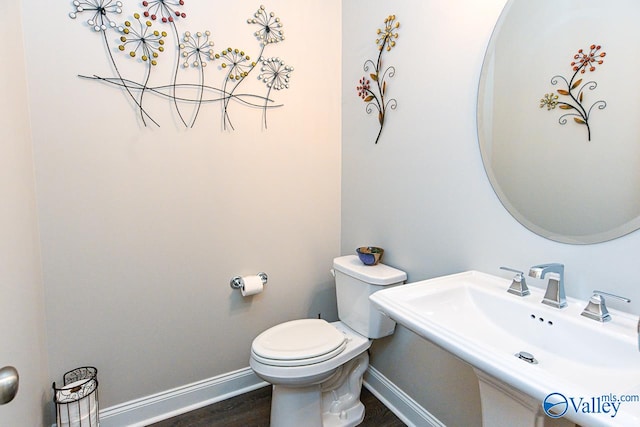 bathroom featuring toilet, sink, and wood-type flooring