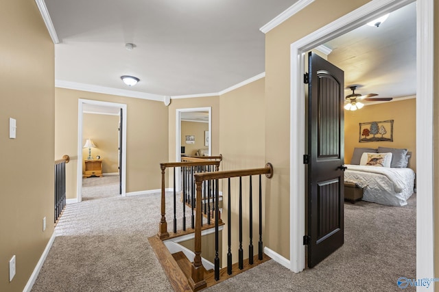 corridor featuring carpet, an upstairs landing, baseboards, and ornamental molding