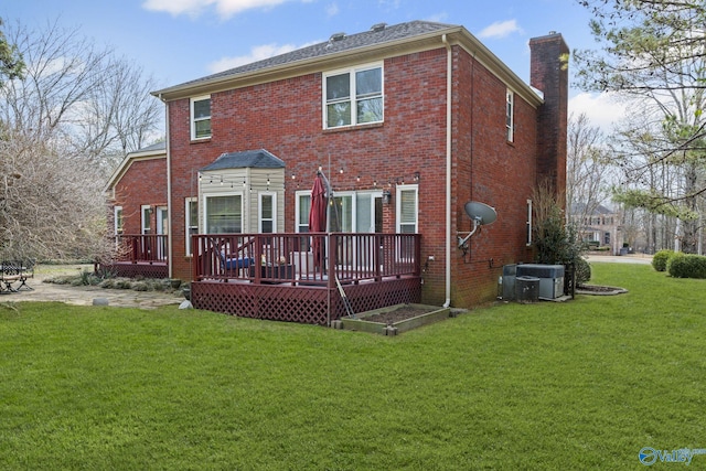 rear view of property with a lawn, brick siding, central AC, and a chimney