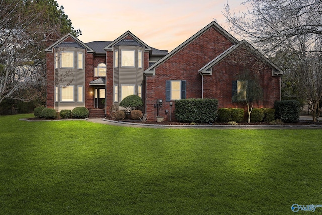 view of front facade with brick siding and a front lawn