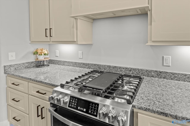 kitchen featuring cream cabinets, stainless steel range with gas cooktop, light stone countertops, and custom exhaust hood