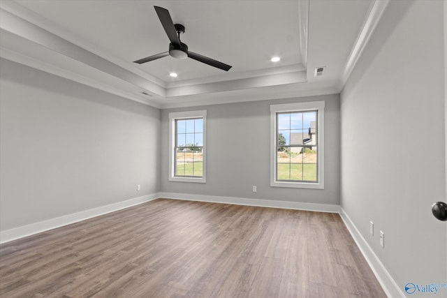 spare room featuring a tray ceiling, ceiling fan, and light hardwood / wood-style floors