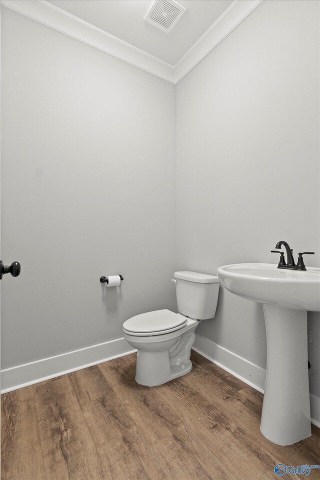 bathroom with crown molding, toilet, and hardwood / wood-style flooring