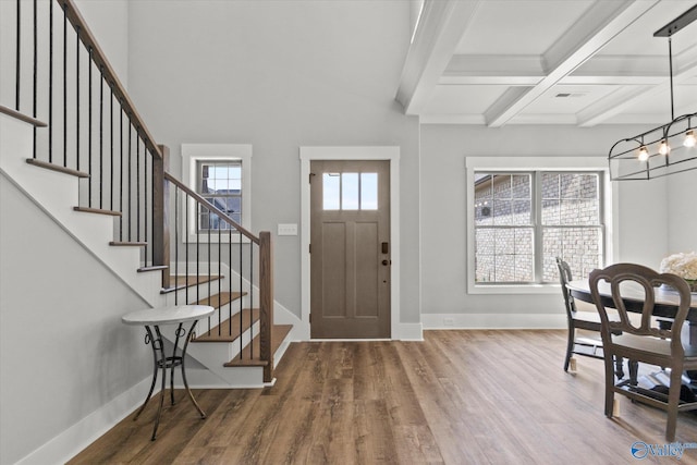 foyer with hardwood / wood-style flooring, beam ceiling, a notable chandelier, and a healthy amount of sunlight