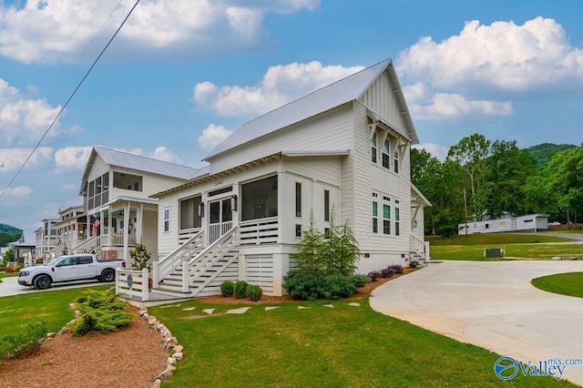 view of side of home with stairs, crawl space, a lawn, a sunroom, and metal roof