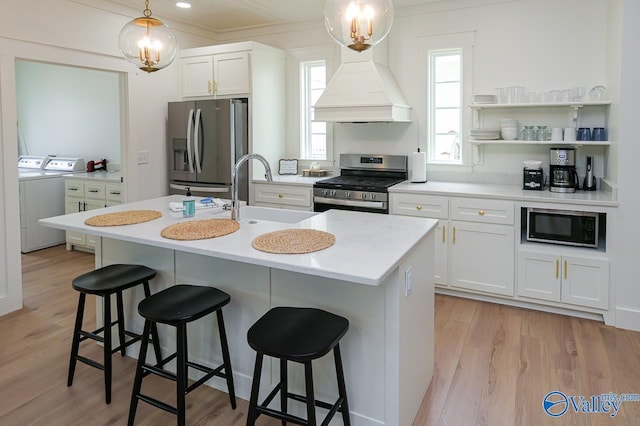 kitchen featuring a sink, washer and dryer, stainless steel appliances, light countertops, and white cabinetry