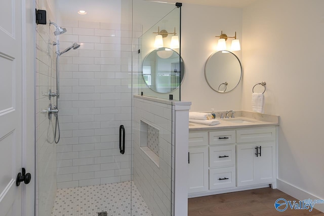 bathroom featuring wood finished floors, vanity, and a shower stall