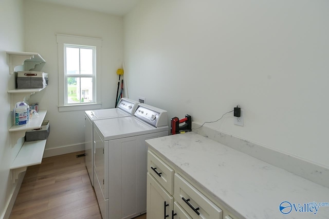 laundry area with baseboards, washing machine and clothes dryer, cabinet space, and light wood-type flooring