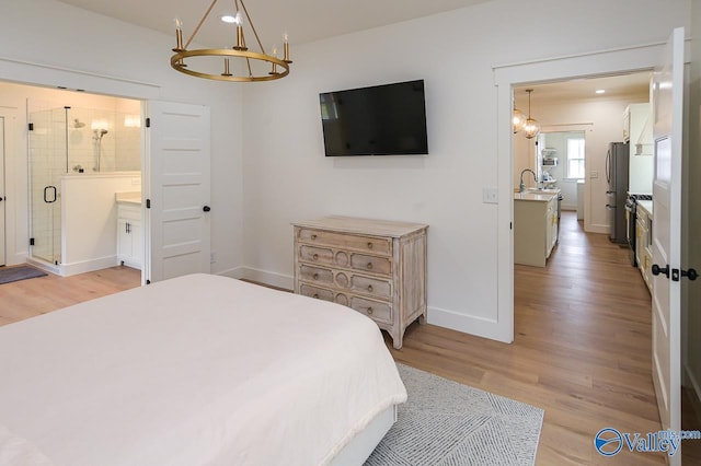 bedroom with baseboards, a notable chandelier, light wood-type flooring, and freestanding refrigerator