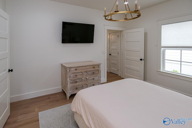 bedroom with baseboards, a chandelier, and light wood-style flooring