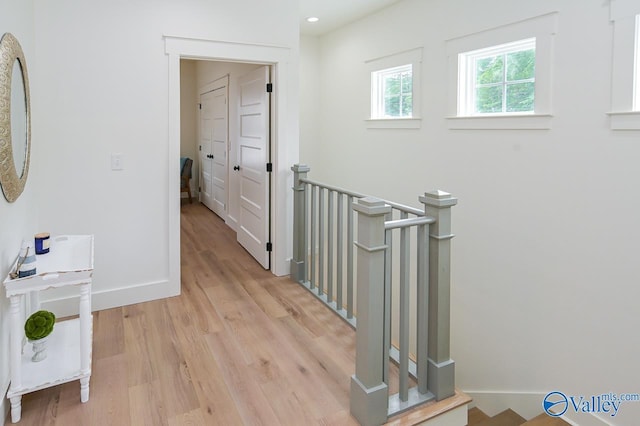 corridor featuring recessed lighting, light wood-style floors, baseboards, and an upstairs landing