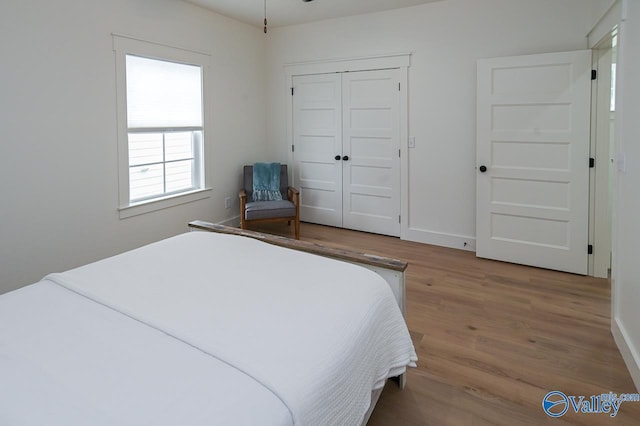 bedroom with wood finished floors, a closet, and baseboards