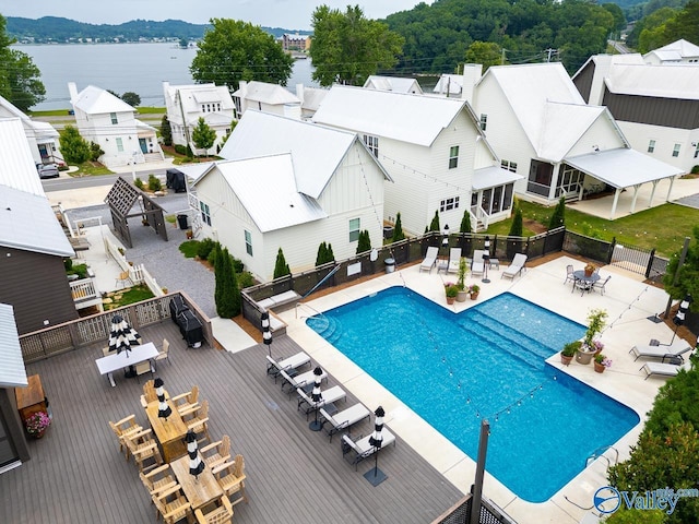 community pool featuring fence, a deck with water view, and a residential view