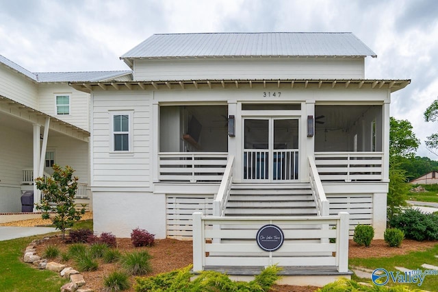 view of front facade with a sunroom, stairway, and metal roof