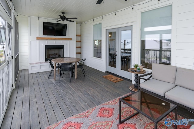 deck featuring an outdoor living space with a fireplace, french doors, outdoor dining area, and ceiling fan
