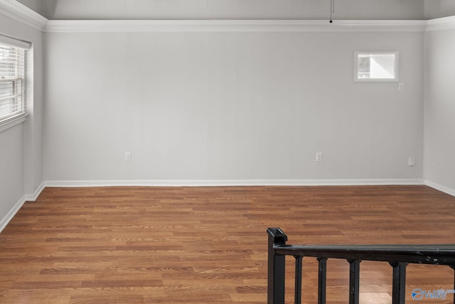 spare room featuring crown molding, wood finished floors, and baseboards