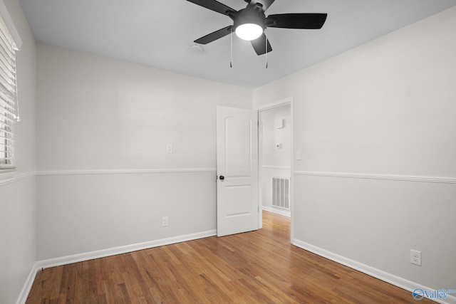 spare room featuring visible vents, ceiling fan, baseboards, and wood finished floors