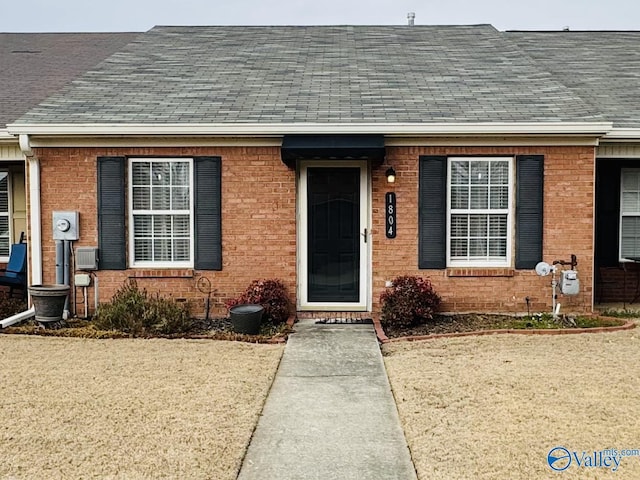 view of front of home with a shingled roof and brick siding