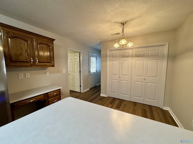 interior space with dark wood finished floors, a closet, visible vents, a textured ceiling, and baseboards