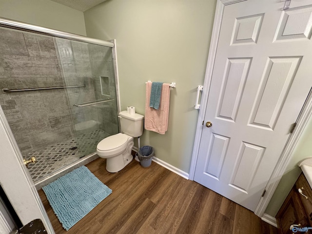 full bath featuring toilet, a stall shower, baseboards, and wood finished floors