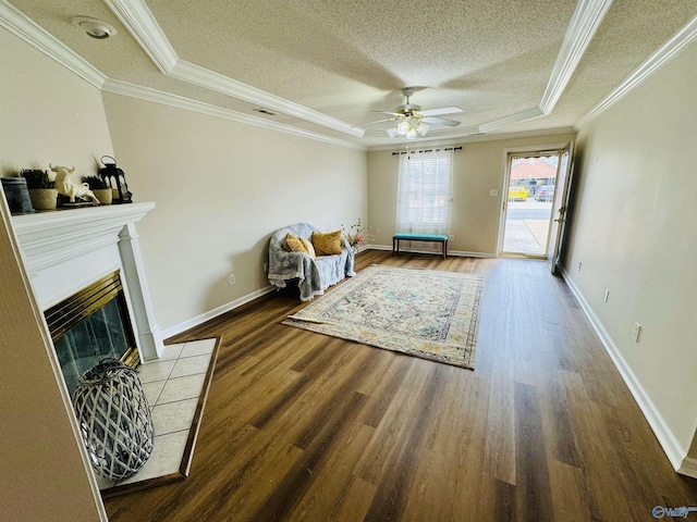 sitting room featuring a textured ceiling, a tiled fireplace, wood finished floors, and crown molding