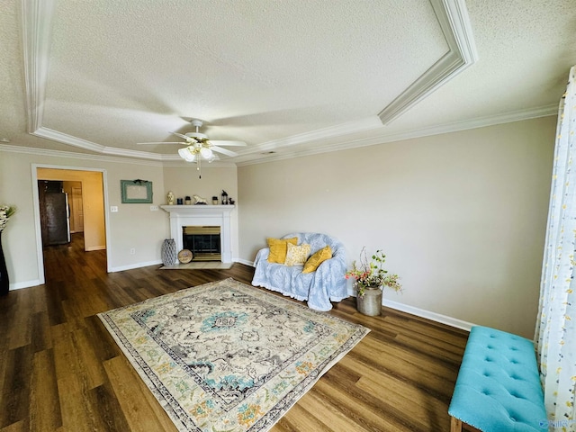 living area with a glass covered fireplace, crown molding, a textured ceiling, and wood finished floors