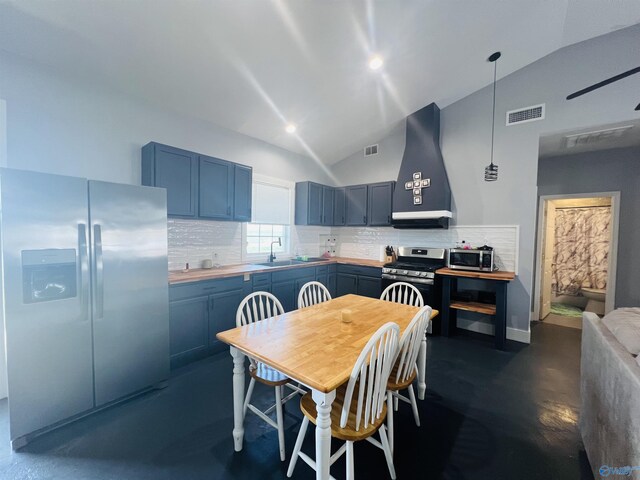 450 County Road 803, Centre, AL 35960 - kitchen featuring tasteful backsplash, blue cabinets, vaulted ceiling, appliances with stainless steel finishes, and wall chimney exhaust hood