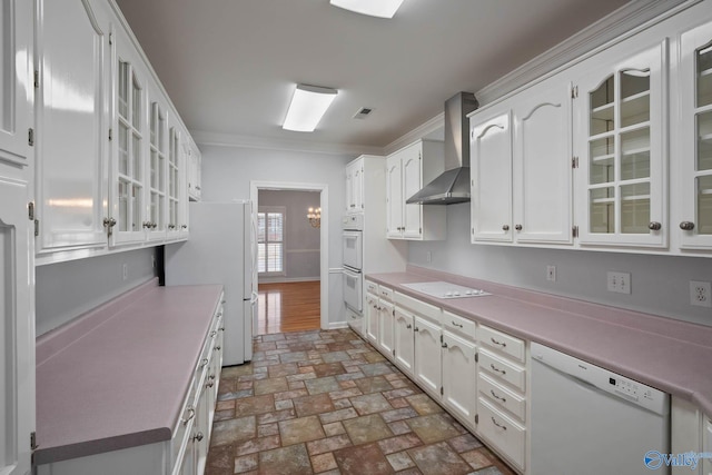 kitchen with wall chimney exhaust hood, ornamental molding, white cabinets, white appliances, and baseboards