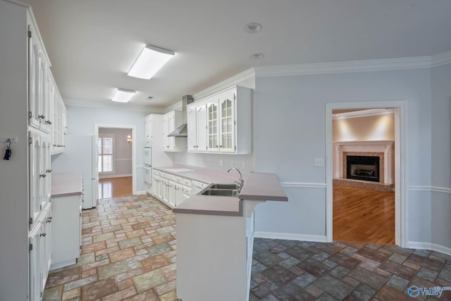 kitchen featuring wall chimney exhaust hood, ornamental molding, a breakfast bar, and a sink