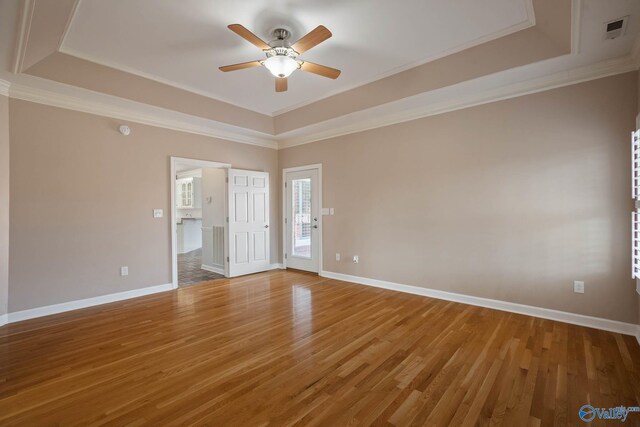 interior space with a tray ceiling, wood finished floors, and baseboards