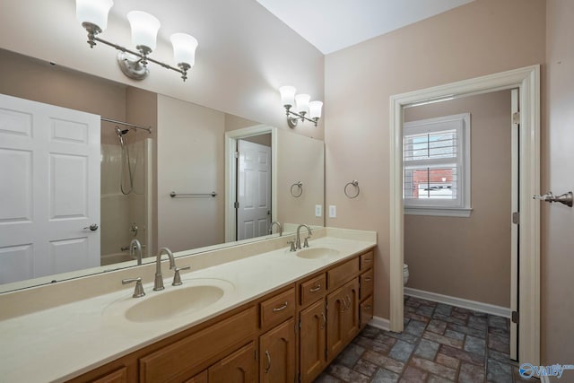 full bathroom featuring baseboards, a sink, toilet, and double vanity