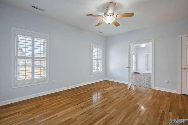 unfurnished room featuring baseboards, visible vents, ceiling fan, and wood finished floors