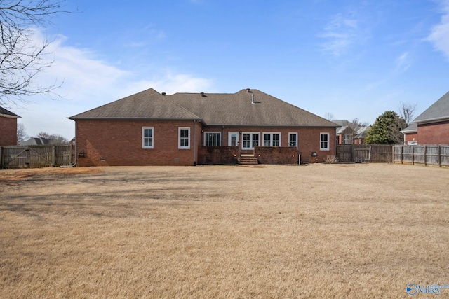 back of house featuring roof with shingles, brick siding, crawl space, and a fenced backyard