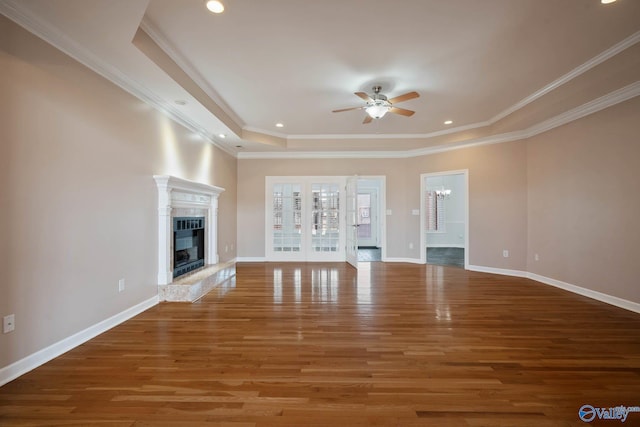 unfurnished living room featuring ceiling fan with notable chandelier, baseboards, wood finished floors, and a glass covered fireplace