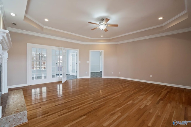 unfurnished living room featuring a fireplace with raised hearth, ceiling fan, wood finished floors, and baseboards