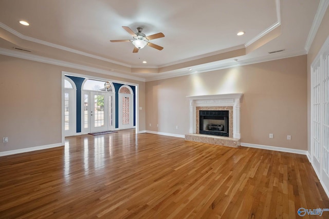 unfurnished living room featuring light wood finished floors, a raised ceiling, a high end fireplace, and baseboards