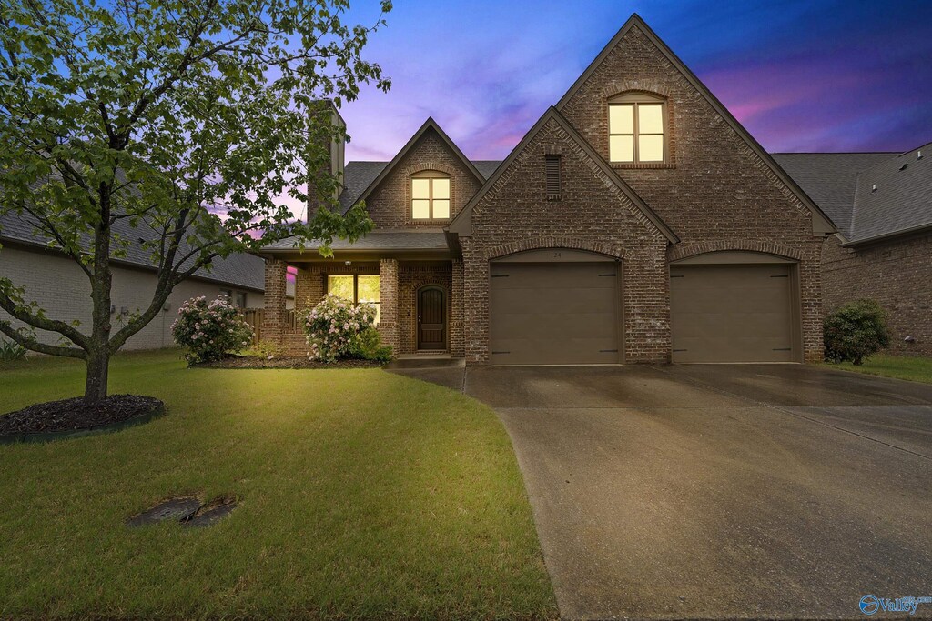124 Rainwood Dr SW, Huntsville, AL 35824 - view of front of home with a front lawn, roof with shingles, a chimney, brick siding, and driveway