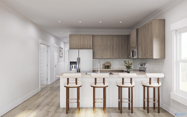 kitchen featuring plenty of natural light, light hardwood / wood-style floors, a kitchen breakfast bar, and stainless steel appliances