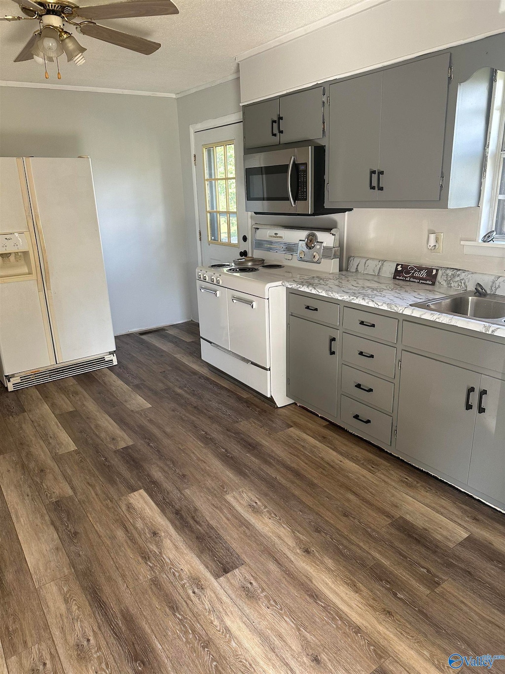 kitchen with dark wood-type flooring, sink, gray cabinetry, ceiling fan, and white appliances