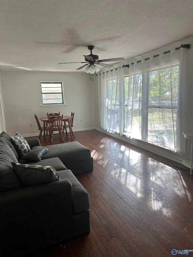 living room with a textured ceiling, dark hardwood / wood-style flooring, and ceiling fan