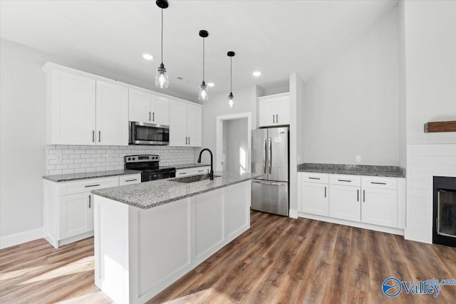 kitchen featuring a kitchen island with sink, stainless steel appliances, a sink, white cabinetry, and pendant lighting