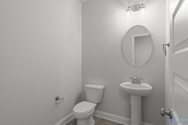 half bath featuring toilet, a sink, baseboards, and tile patterned flooring