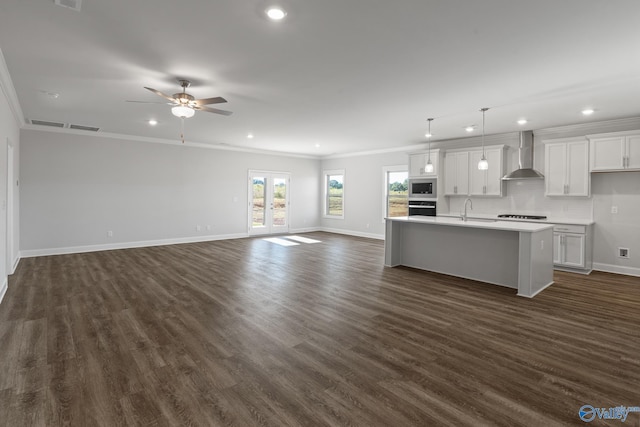 kitchen featuring open floor plan, light countertops, wall chimney exhaust hood, and black oven