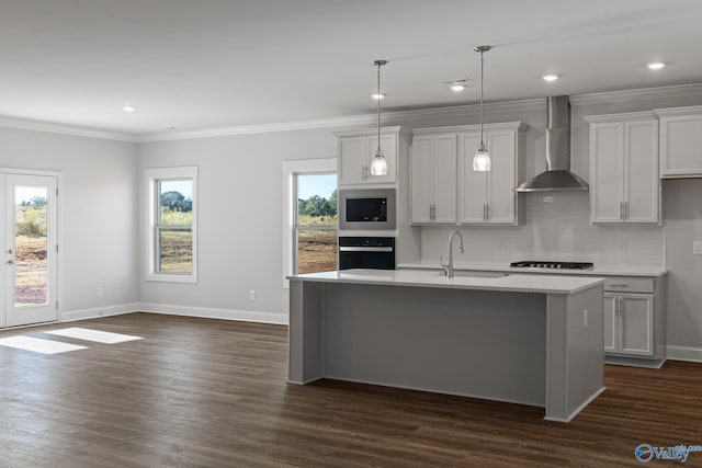 kitchen featuring oven, a sink, wall chimney range hood, light countertops, and stainless steel microwave