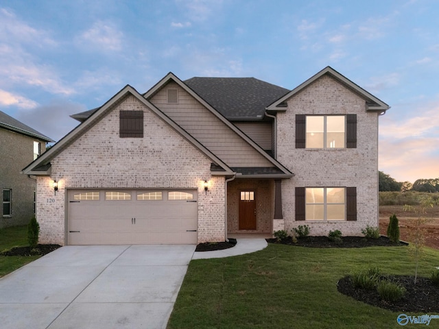 view of front of house with a shingled roof, a yard, a garage, concrete driveway, and brick siding