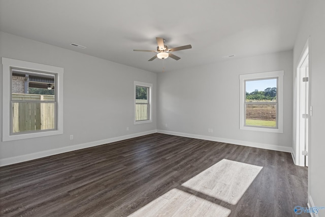 empty room with plenty of natural light, dark wood-type flooring, and baseboards